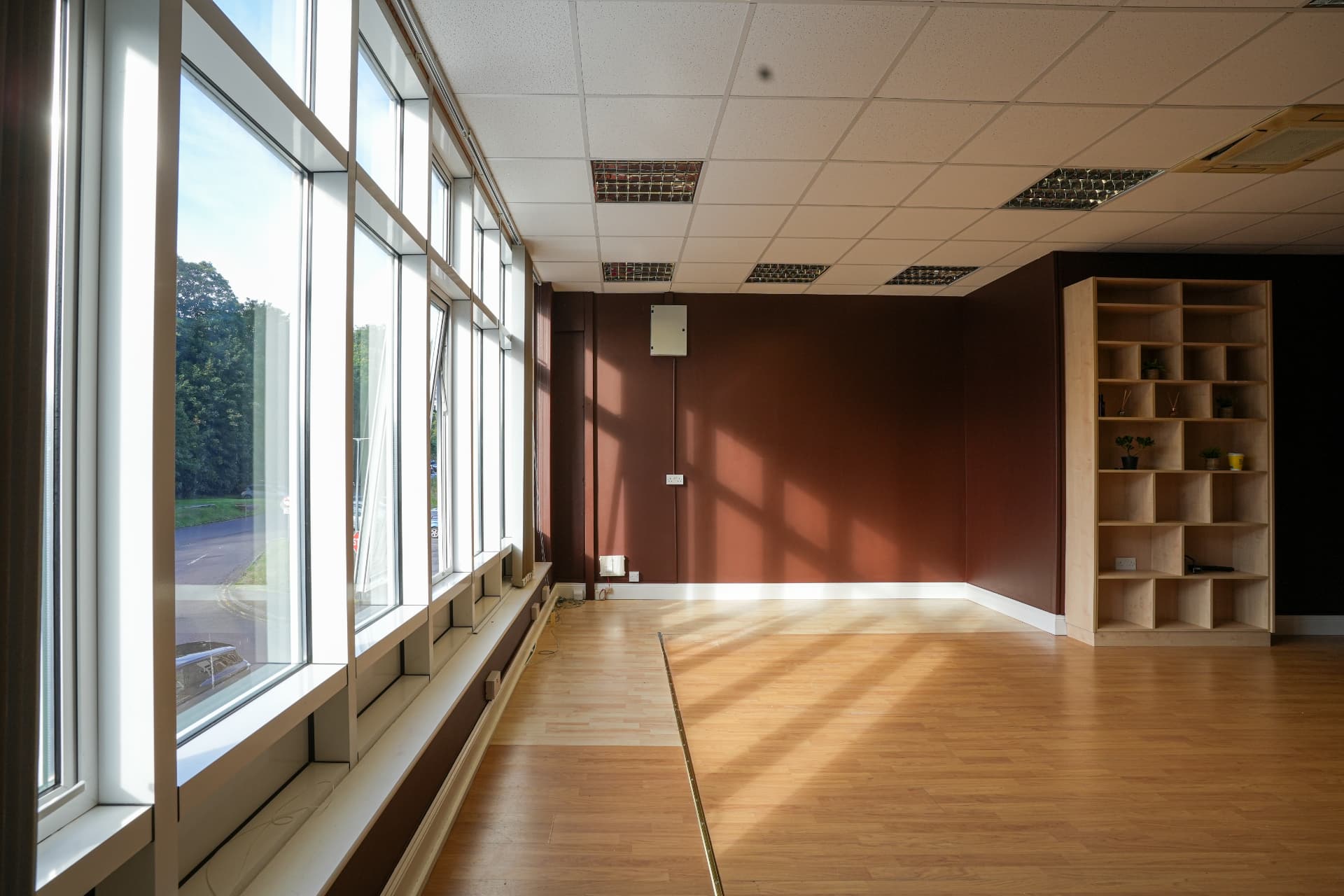 The main studio with tall windows, wooden floor and sunlit cocoa wall